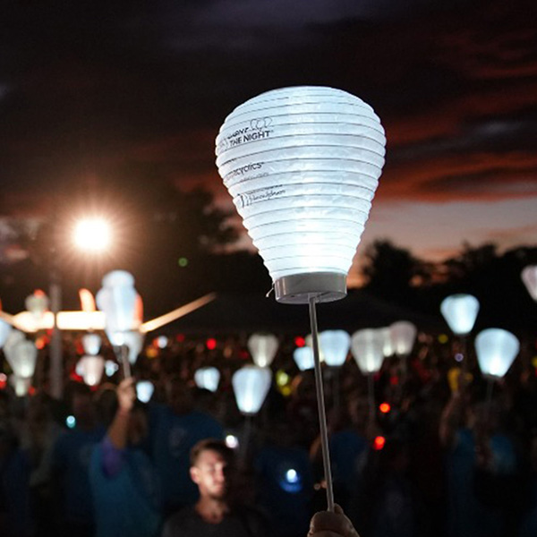 Handheld lanterns filling a park at night.