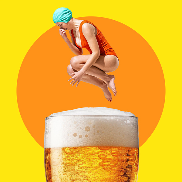 Woman in an orange swimsuit and blue swim cap doing a cannonball in a large glass of beer.