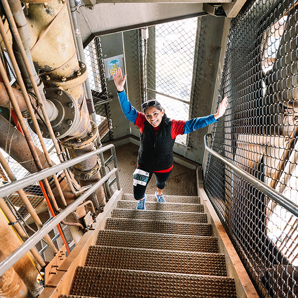 Excited female athlete climbing metal steps.