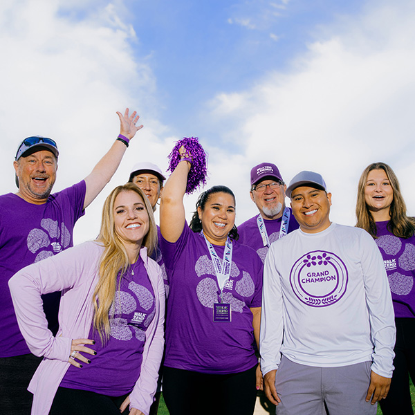 Diverse group of happy people wearing purple and gray clothing.
