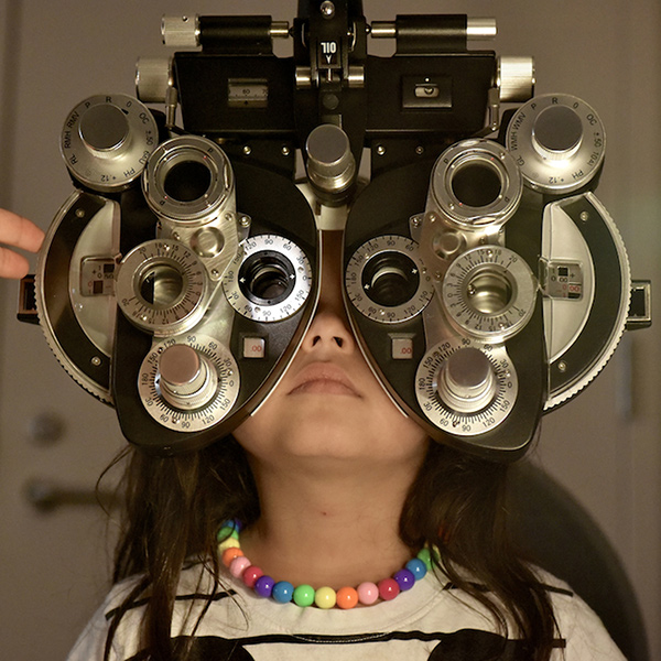 a young patient sits behind an eye exam machine