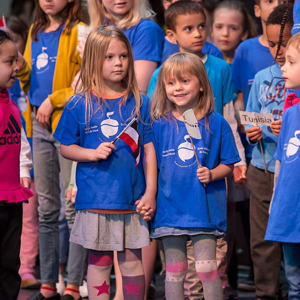 Children in blue t-shirts holding small flags