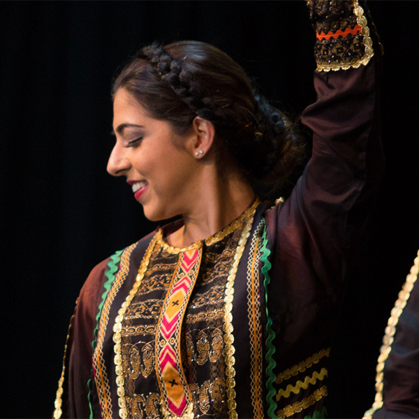 Middle eastern woman wearing an outfit with complex patterns and performing a dance.