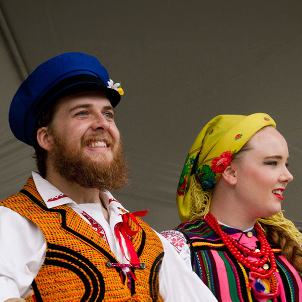 A white man and woman smiling, wearing traditional Polish outfits.