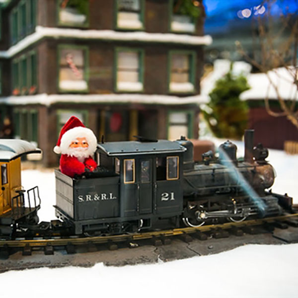 Minature building with a train car gliding past with santa claus sitting on the engine