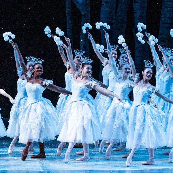 Ballet dancers with arms raised in a forest