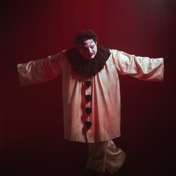 Angry man in clown costume with arms raised